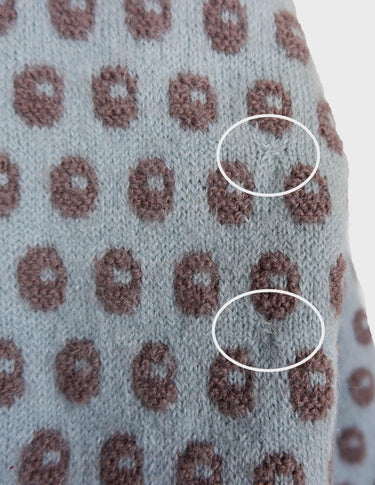 a woman is wearing a light blue vintage sweater.