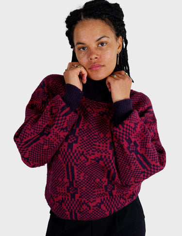 a woman is wearing a 80s dark pink geometric turtleneck sweater.