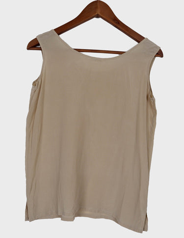a woman is wearing a beige vintage 90s silk top.