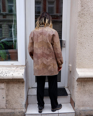 This vintage 80s leather jacket features a unique brown patchwork design and a real fur lining for added warmth and luxury.