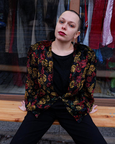 Add a touch of vintage glamour to your wardrobe with our 80s inspired velvet blazer. The delicate floral pattern features a subtle shimmer, adding a touch of luxury to this thin jacket. Perfect for a playful yet sophisticated look. Please keep in mind that the shimmering outerline of the flowers feels a bit scratchy.