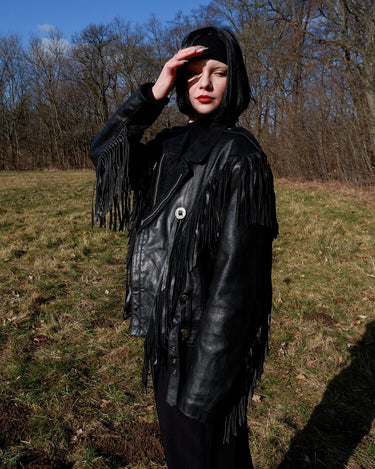 Add some wild vibes to your wardrobe with this vintage 80s 90s black fringe leather jacket. Complete with conchos and a belt, this jacket will be a statement piece for any outfit.