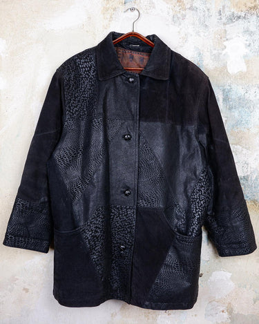 This vintage black leather coat blends matte suede leather with subtly glossy smooth leather panels in rich black tones. The unique patchwork design, featuring delicate dot-textured sections, adds depth, texture, and quiet individuality. With its sleek cut, button front, and spacious pockets, this timeless piece is full of character – perfect for those who appreciate quality and one-of-a-kind style.