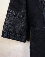 This vintage black leather coat blends matte suede leather with subtly glossy smooth leather panels in rich black tones. The unique patchwork design, featuring delicate dot-textured sections, adds depth, texture, and quiet individuality. With its sleek cut, button front, and spacious pockets, this timeless piece is full of character – perfect for those who appreciate quality and one-of-a-kind style.