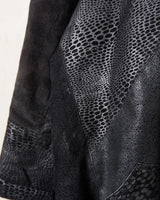 This vintage black leather coat blends matte suede leather with subtly glossy smooth leather panels in rich black tones. The unique patchwork design, featuring delicate dot-textured sections, adds depth, texture, and quiet individuality. With its sleek cut, button front, and spacious pockets, this timeless piece is full of character – perfect for those who appreciate quality and one-of-a-kind style.