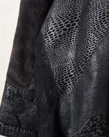 This vintage black leather coat blends matte suede leather with subtly glossy smooth leather panels in rich black tones. The unique patchwork design, featuring delicate dot-textured sections, adds depth, texture, and quiet individuality. With its sleek cut, button front, and spacious pockets, this timeless piece is full of character – perfect for those who appreciate quality and one-of-a-kind style.