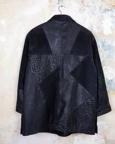 This vintage black leather coat blends matte suede leather with subtly glossy smooth leather panels in rich black tones. The unique patchwork design, featuring delicate dot-textured sections, adds depth, texture, and quiet individuality. With its sleek cut, button front, and spacious pockets, this timeless piece is full of character – perfect for those who appreciate quality and one-of-a-kind style.