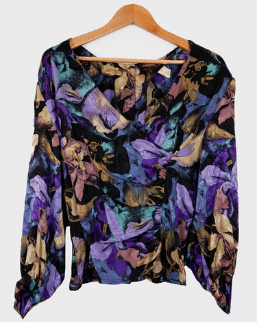 Flower power! This vintage, floral-patterned blouse is made from pure silk, and features dramatic shoulder pads and a button row at the back. Experience '80s elegance with a modern twist! #teamshoulderpads