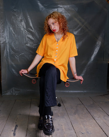 This vintage 90s orange blouse will add a pop of color to your wardrobe. The short sleeves and viscose mix fabric make it lightweight and perfect for any casual occasion!