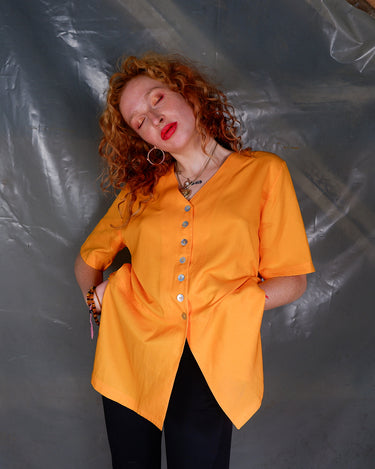 This vintage 90s orange blouse will add a pop of color to your wardrobe. The short sleeves and viscose mix fabric make it lightweight and perfect for any casual occasion!