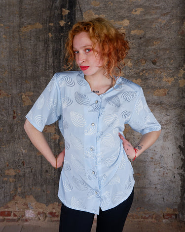 Introduce some sparkle to your style with this vintage 80s light blue blouse. The flattering fit, courtesy of the short sleeves and shoulder pads, meets a playful touch of shimmering pattern. Sparkle on!
