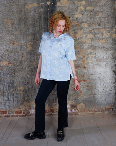 Introduce some sparkle to your style with this vintage 80s light blue blouse. The flattering fit, courtesy of the short sleeves and shoulder pads, meets a playful touch of shimmering pattern. Sparkle on!