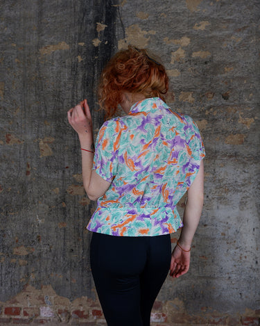 Add a pop of color to your wardrobe with this Vintage 80s colorful short sleeve blouse! Its diagonal button row adds a unique touch, and the lightweight fabric ensures comfort all day long. A fun and playful addition to any outfit.