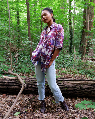 This 1990s Thai silk shirt with its chest pocket showcases a vibrant bird-and-leaf pattern in rich purples, reds, and blues. The luxurious silk fabric offers a smooth, lightweight feel with an eye-catching, exotic flair. Vintage, loud, and anything but boring.&nbsp;