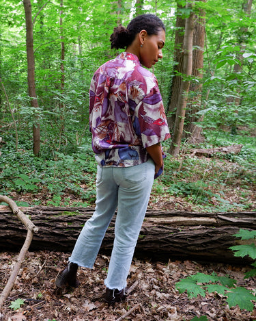 This 1990s Thai silk shirt with its chest pocket showcases a vibrant bird-and-leaf pattern in rich purples, reds, and blues. The luxurious silk fabric offers a smooth, lightweight feel with an eye-catching, exotic flair. Vintage, loud, and anything but boring.