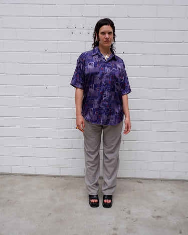 Bold, breezy, and silky smooth - this rare 90s short-sleeve gem by T. Corner is made from real Thai silk, brought to you by one of Thailand’s most renowned silk producers. The glossy fabric pops with a crazy pattern in electric purples and blues that’s impossible to ignore. Wear it loud, wear it proud!