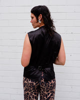 This Y2k black vest blends classic baroque style with a subtle gothic edge. The textured floral pattern and fleur-de-lis buttons give it a refined yet bold character. Cool, confident and a little unexpected – a standout piece without shouting.