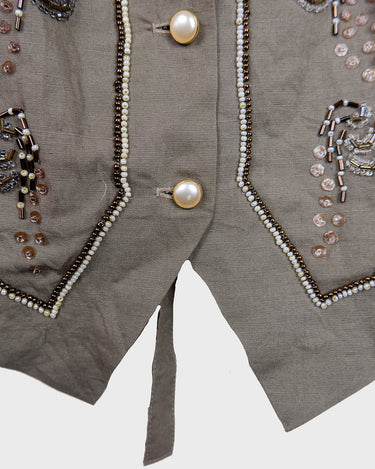 Fine beadwork and soft sequins give this 90s brown-grey waistcoat its understated shine – subtle, but impossible to miss. With a paisley satin back and belt, it’s a thoughtful piece for those who appreciate timeless style and fine detail.