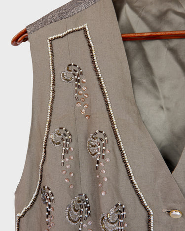 Fine beadwork and soft sequins give this 90s brown-grey waistcoat its understated shine – subtle, but impossible to miss. With a paisley satin back and belt, it’s a thoughtful piece for those who appreciate timeless style and fine detail.