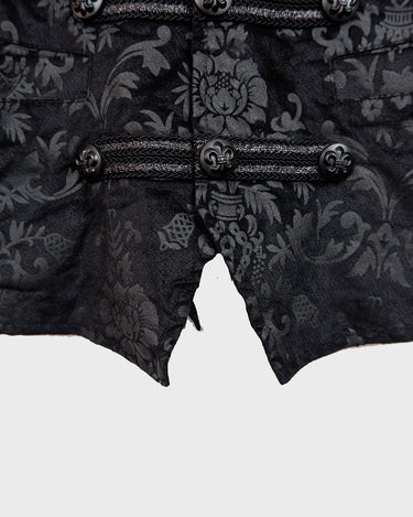 This Y2k black vest blends classic baroque style with a subtle gothic edge. The textured floral pattern and fleur-de-lis buttons give it a refined yet bold character. Cool, confident and a little unexpected – a standout piece without shouting.