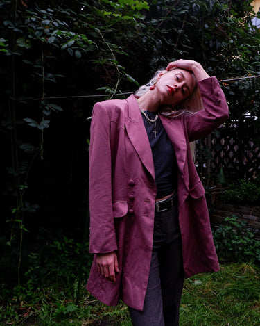This vintage blazer in a striking dark pink is a must-have for any fashion-forward individual. Its long fit and two rows of buttons add a unique twist to any outfit. Whether you're dressing up for a formal event or adding some flair to your everyday look, this blazer has got you covered. (No time for boring fashion here!)