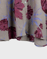 1980s vintage silk blouse with a loose fit and floral print in burgundy-violet on taupe. The silk adds a natural sense of luxury and ease. A laid-back piece with quiet elegance and vintage character.