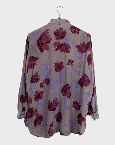 1980s vintage silk blouse with a loose fit and floral print in burgundy-violet on taupe. The silk adds a natural sense of luxury and ease. A laid-back piece with quiet elegance and vintage character.