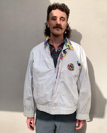 This vintage Missoni Sport windbreaker from the 90s is a standout piece with its bold striped accents and iconic globe logo embroidery. Made in Italy and cut in a comfortable size L, it offers a relaxed fit and lightweight feel – ideal for everyday wear. A rare example of Missoni’s sporty aesthetic, combining timeless design with a splash of color. Effortlessly cool and easy to style.