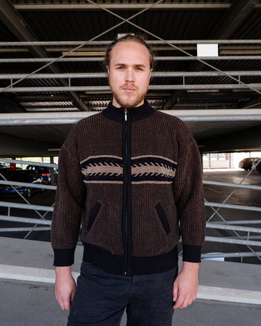 Looking to add a timeless vintage piece to your wardrobe? This original 80s zip-up knit jacket features a rich brown tone with black accents and a bold geometric stripe across the chest. The thick ribbed texture and relaxed fit deliver effortless old-school cool with a cozy feel.