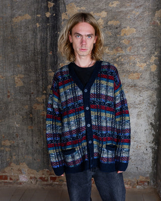 This vintage knit cardigan features a balanced multicolor pattern in navy, red, teal and yellow with a clean geometric stripe design. The knit and classic button-up fit make it an easy, well-made layering piece with subtle character. A quality vintage cardigan for everyday wear with just the right amount of personality.