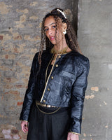 This vintage 80s cropped leather jacket comes in sleek black with subtle gold-tone details for a clean look. Made from thin, lightweight leather, it features a sharp cropped fit and a classic 80s silhouette with a cool, understated edge. Easy to layer and easy to style!