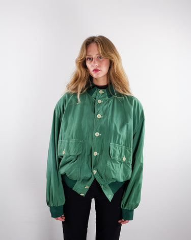 a woman is wearing a Vintage 80s green silk bomber jacket with shoulder pads (custom hand-dyed) | M-L from the online shop vintivintage.com