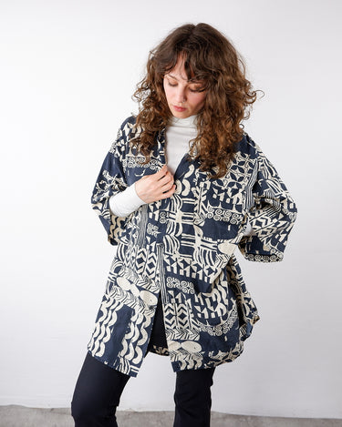 a woman with curls is wearing a Vintage 90s navy blue and cream/white geometric pattern oversized silk shirt in size XL fromt the online shop www.vintivintge.com