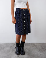 a woman is wearing a navy blue polka midi skirt