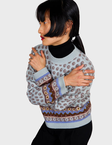 a woman is wearing a light blue vintage sweater.
