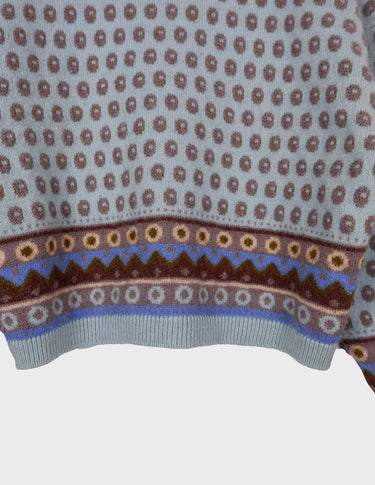 a woman is wearing a light blue vintage sweater.