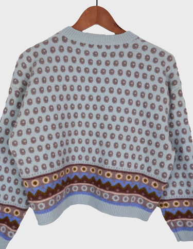 a woman is wearing a light blue vintage sweater.
