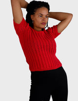 a woman is wearing a red handknitted shirt.
