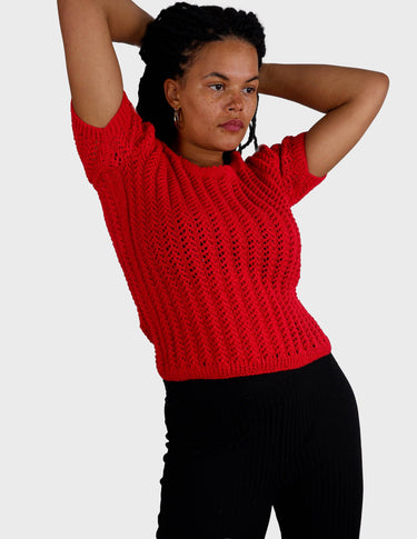 a woman is wearing a red handknitted shirt.