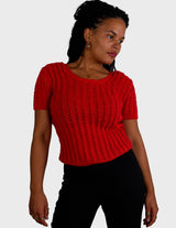 a woman is wearing a red handknitted shirt.