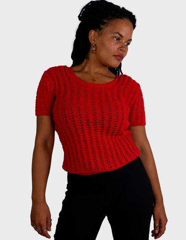 a woman is wearing a red handknitted shirt.