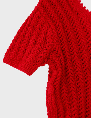 a woman is wearing a red handknitted shirt.