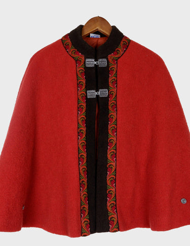 a woman is wearing a red brown boho poncho.