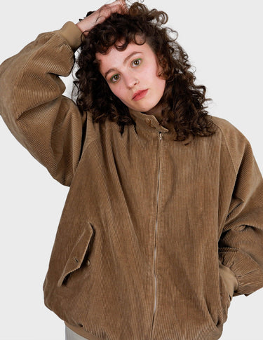 a woman is wearing a brown vintage bomber cord jacket.